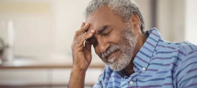 An older man with his hand on his forehead